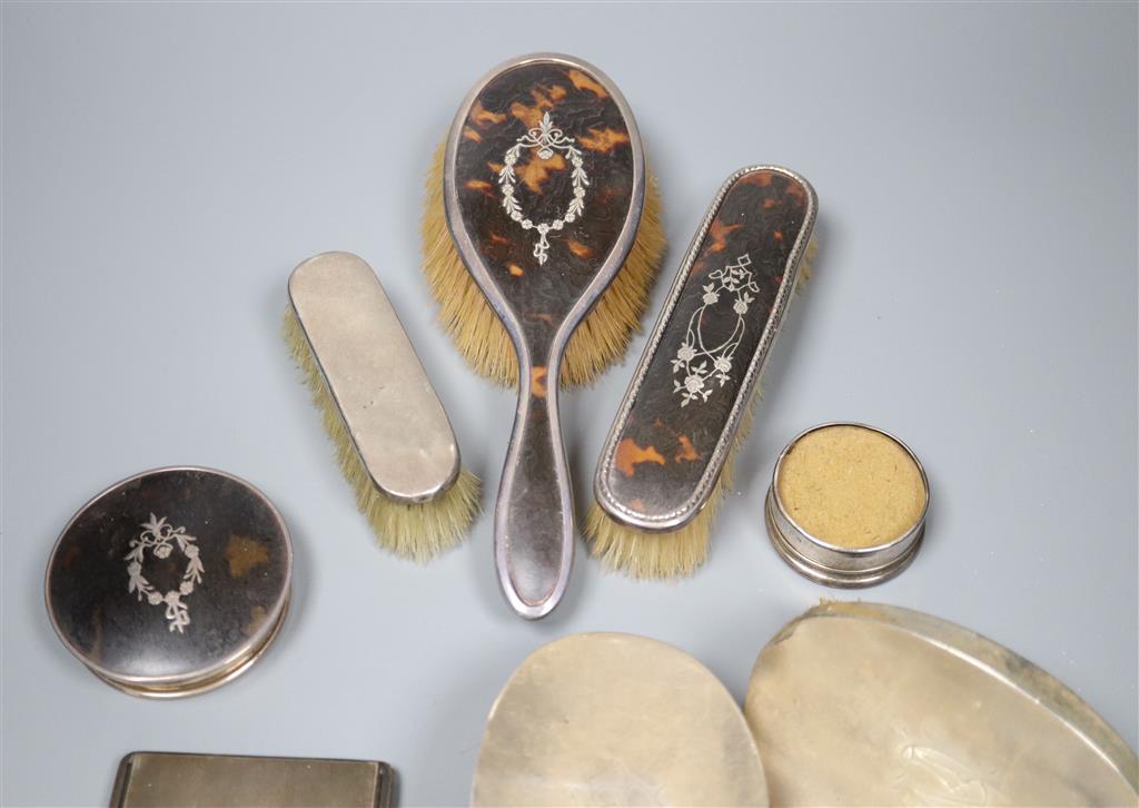 A George V silver cigarette case, five various silver backed brushes and two silver mounted jar tops.